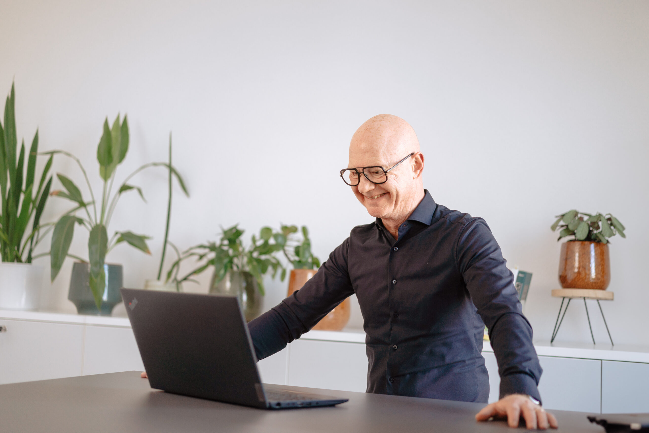 Ablauf MyCulture Kulturanalyse Geschäftsmann arbeitet konzentriert an Laptop in heller Büroumgebung mit Pflanzen an der Auswertung einer Kulturanalyse