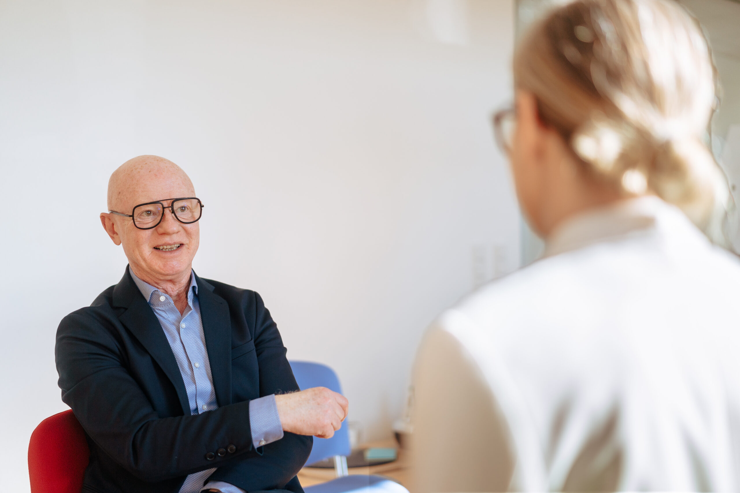 Mehrwert MyJourney Entwicklungsgespräch mit einem Personalentwickler, der freundlich und engagiert mit einer Frau spricht; beide sitzen in einem hellen, modernen Büro