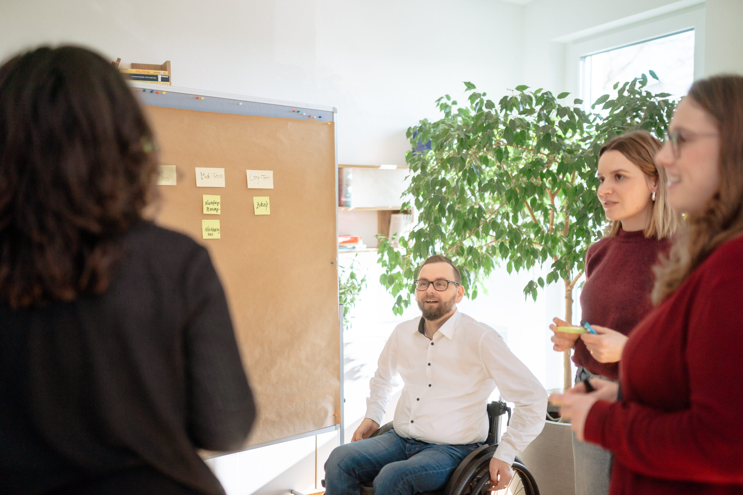 Mehrwert hr_Dia2log HR-Analyse Vier Personen diskutieren gemeinsam vor Pinnwand mit Notizen in heller moderner Büroumgebung Maßnahmen für die Weiterentwicklung von einer HR-Abteilung
