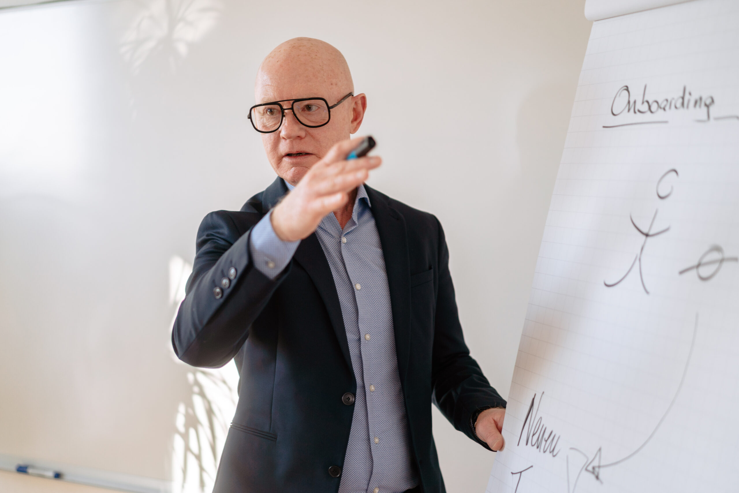 Überblick Retention Management Berater steht vor einem Flipchart, erklärt anwesenden Personen die Bedeutung von Onboarding im gesamten Retention Management Prozess